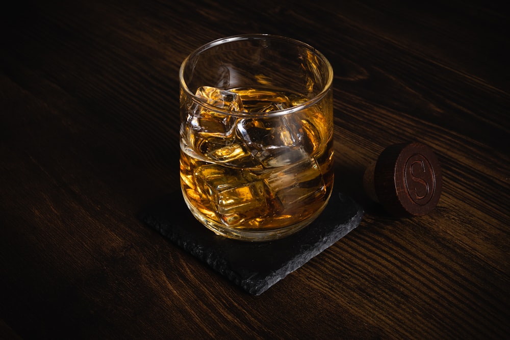 a glass of whiskey sitting on top of a wooden table