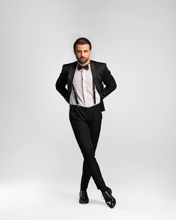 Man posing in a formal tuxedo, an example of black-tie-optional attire for gentlemen