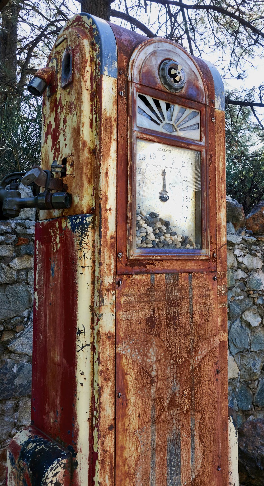 an old rusted out gas pump next to a tree