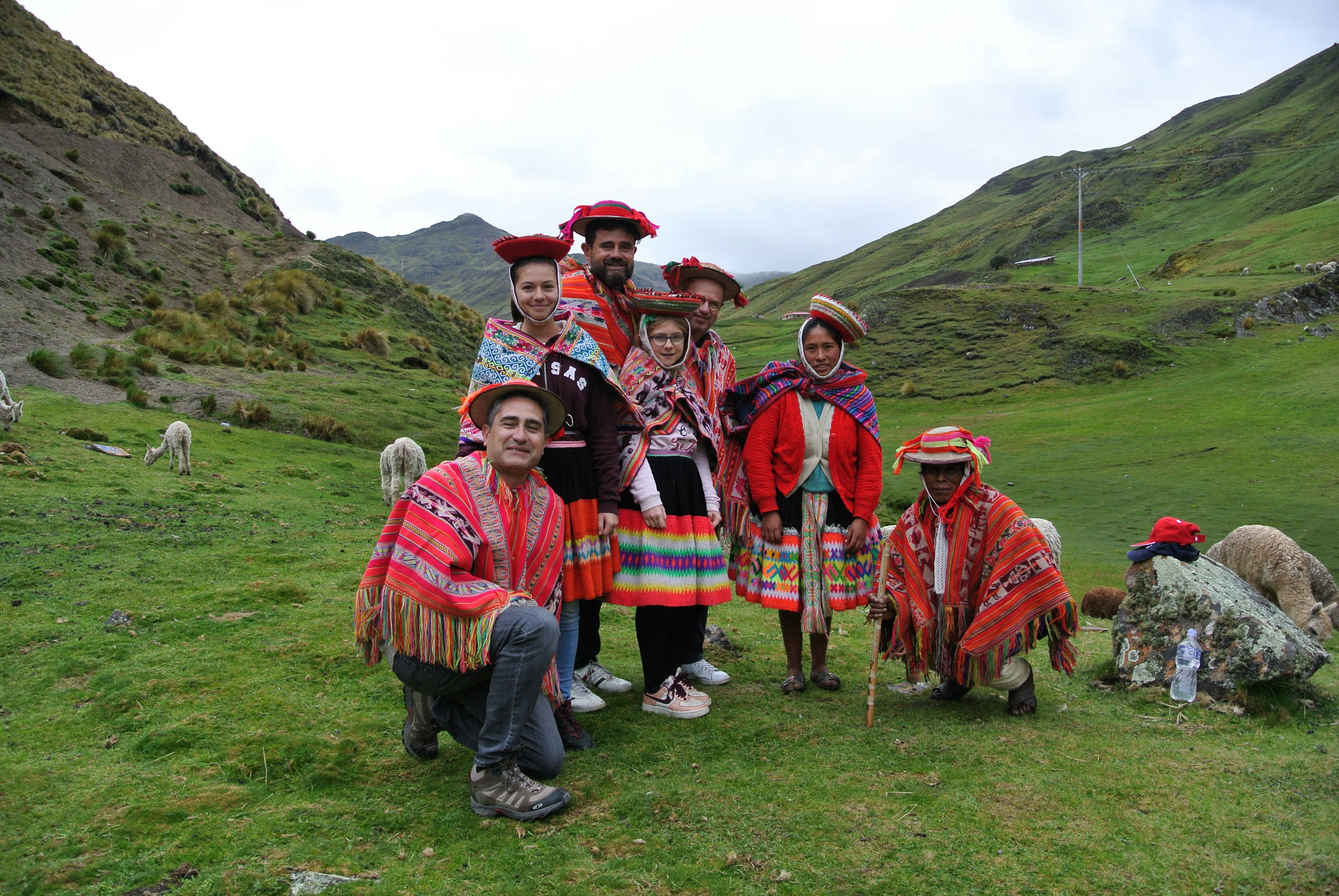 a group of people standing on top of a lush green hillside