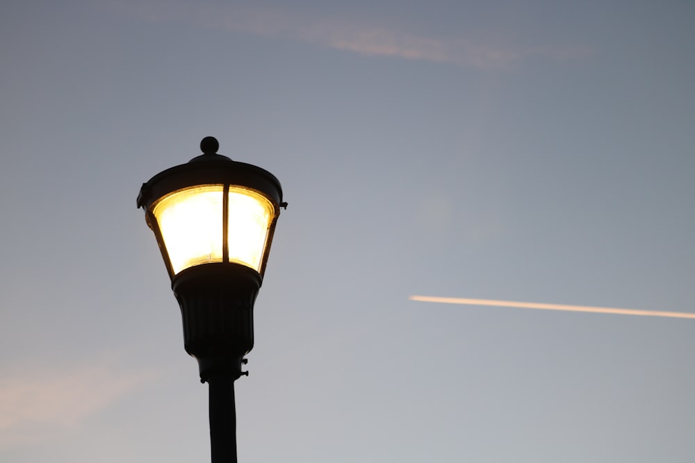a street light with an airplane in the background
