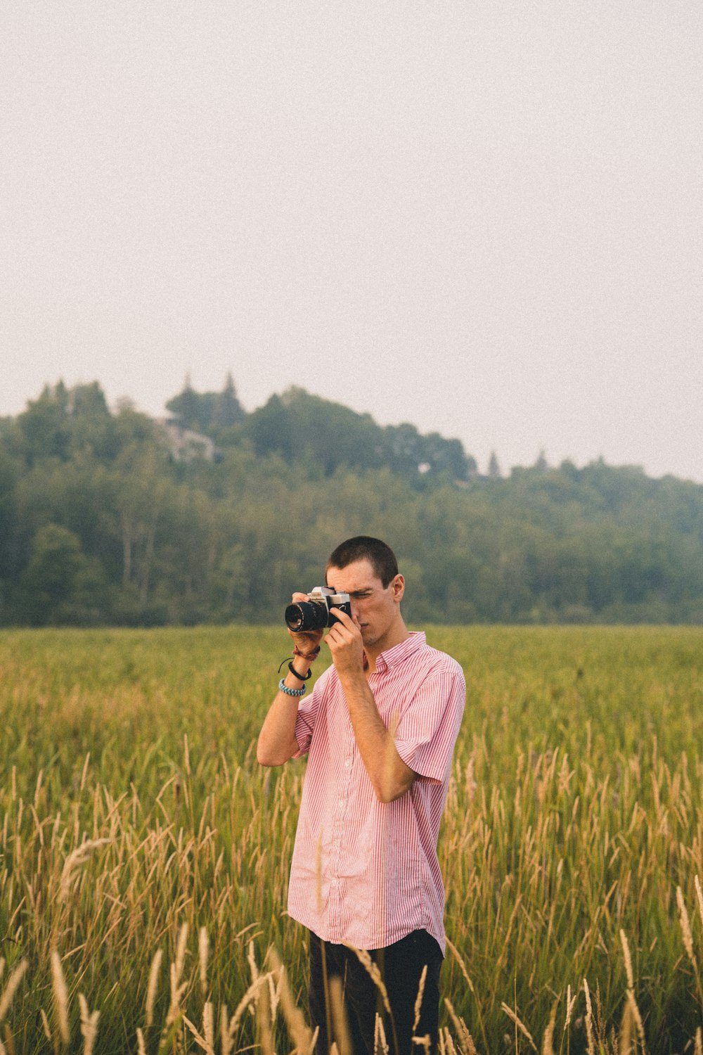 a man standing in a field holding a camera