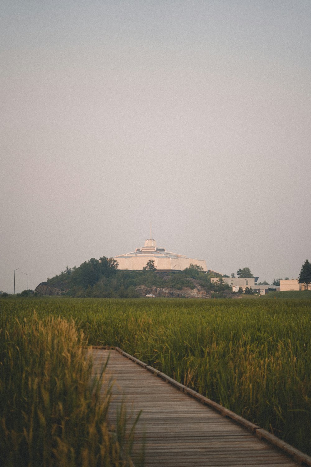 a wooden walkway leading to a large building on a hill