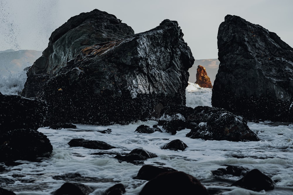 a person standing on a rocky beach next to a body of water