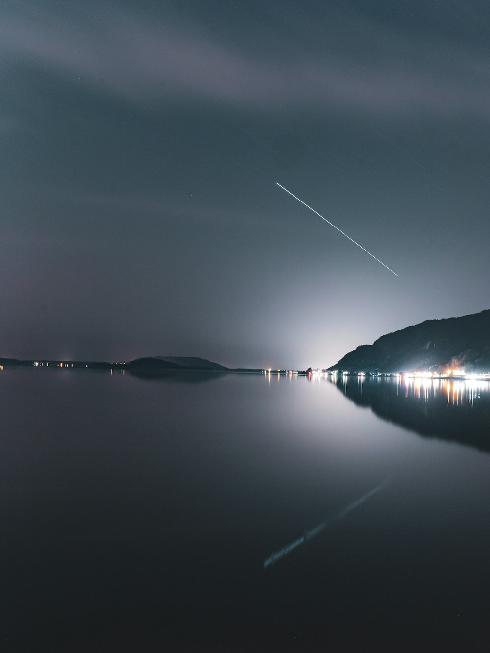 an airplane flying over a body of water at night