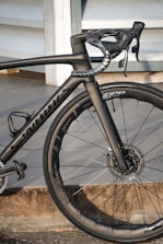 A high-performance road bicycle with a sleek black frame and aerodynamic design, featuring carbon fiber components and disc brakes. The bike is equipped with Zipp wheels, showcasing precision engineering and attention to detail.