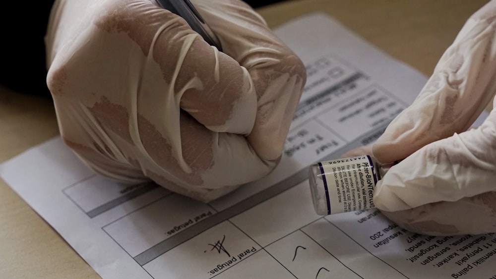 a pair of gloves holding a pen and writing on a piece of paper