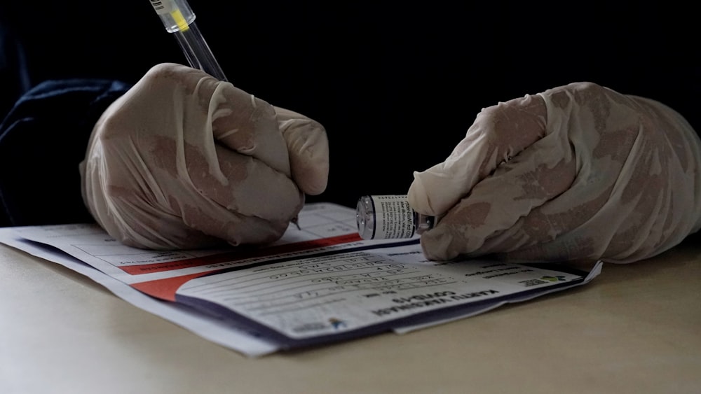 eine Person in Handschuhen, die auf ein Blatt Papier schreibt