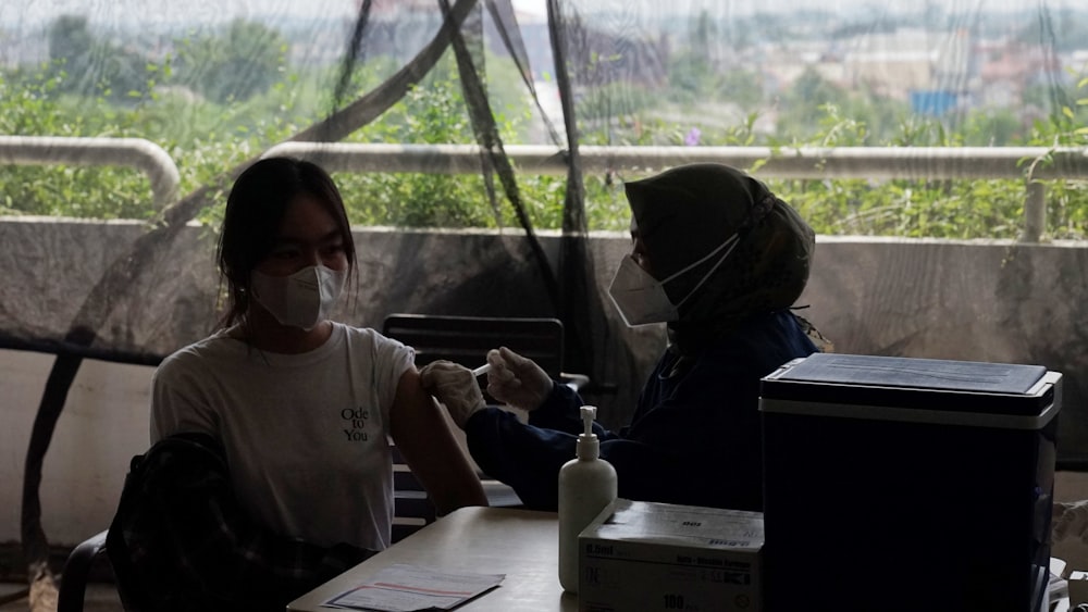 two people sitting at a table with masks on