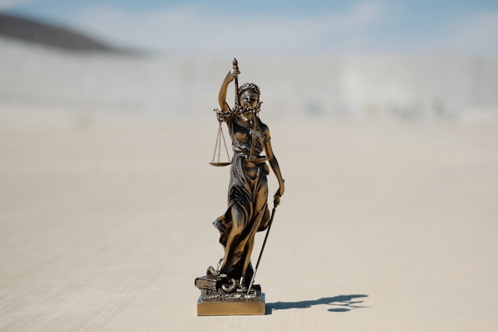 A figure of Lady Justice stands in a desert.