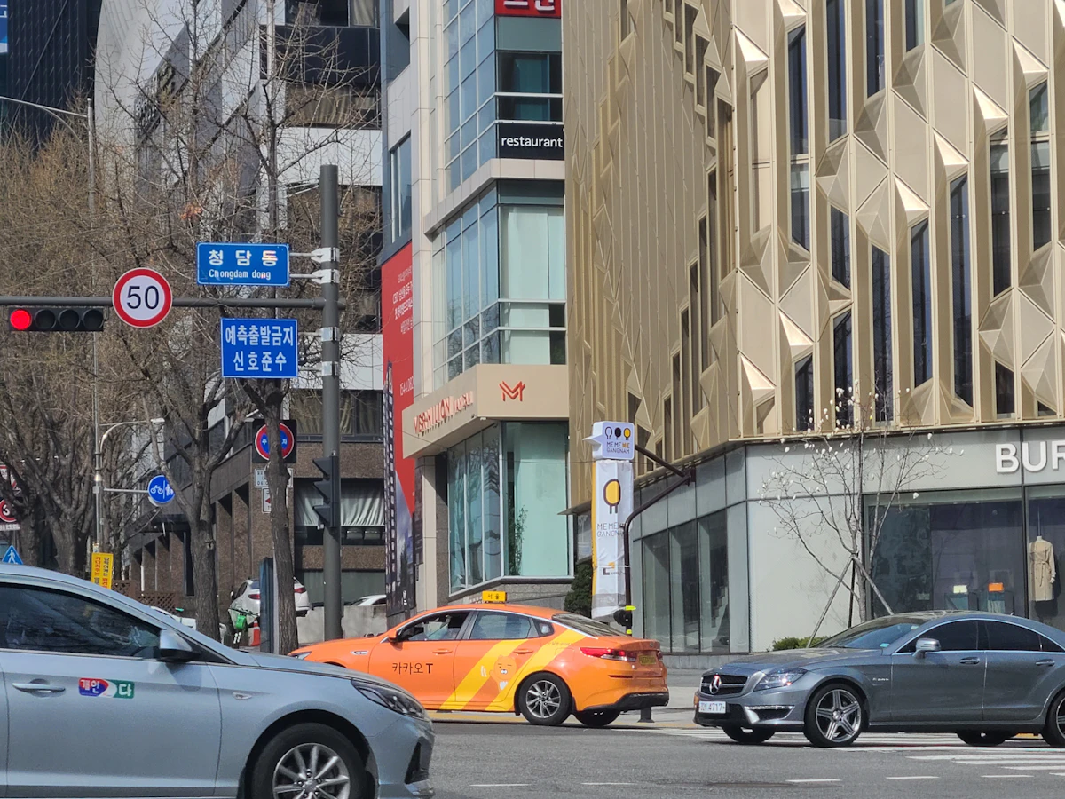 Cheongdam intersection by day with a Burberry store, glass buildings and a Kakao taxi