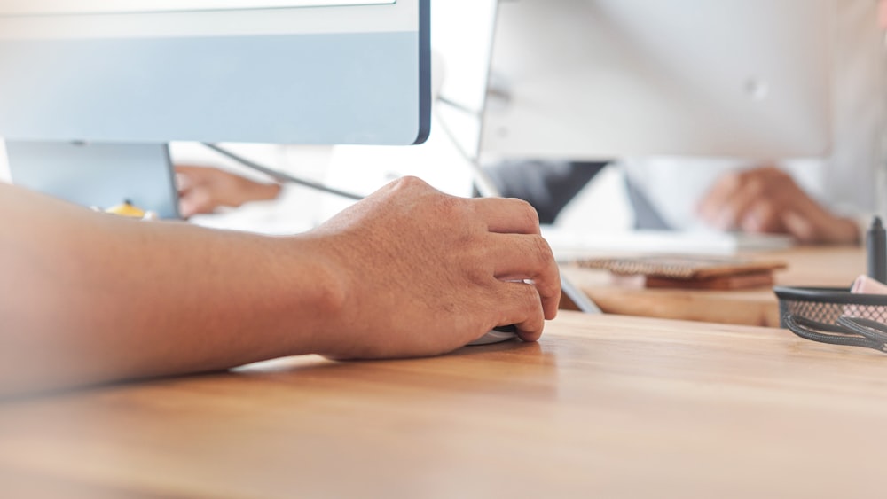 a person using a computer on a wooden desk