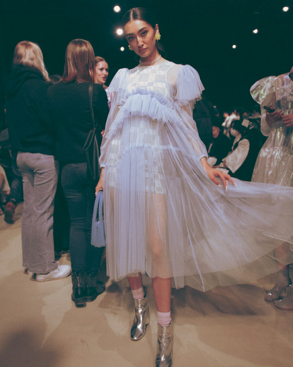 a woman in a white dress standing in front of a group of people