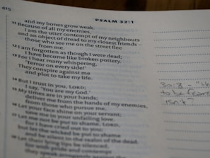 An open page of a book displaying text from a biblical psalm. The page includes verse numbers and a section for notes with handwriting visible on the right. The main text discusses themes of weakness, enemies, and trust in God.