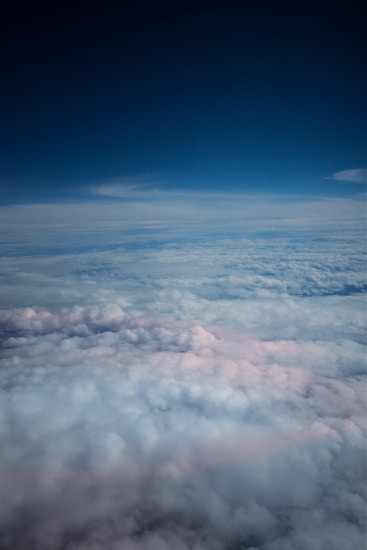 A vast expanse of fluffy clouds seen from above, with a clear blue sky stretching out above them. The clouds appear dense and have a soft, cotton-like texture.