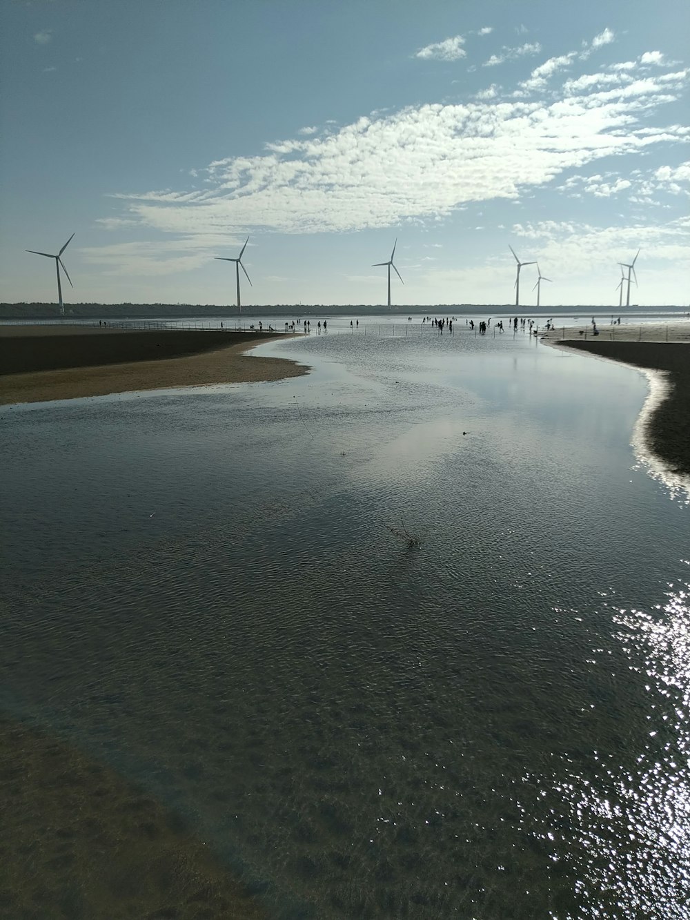 a body of water with wind mills in the background