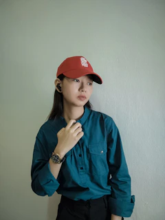 A confident customer wearing a red Triggered Apparel hat against a rustic wooden background.