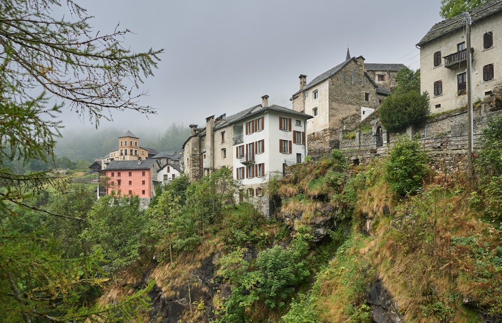 a row of buildings sitting on top of a lush green hillside