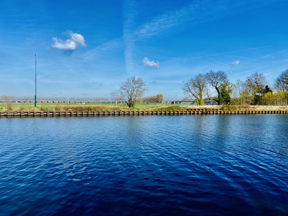 a body of water surrounded by a lush green field