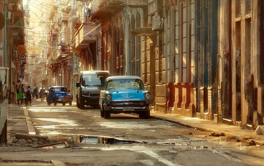 a blue car driving down a street next to tall buildings