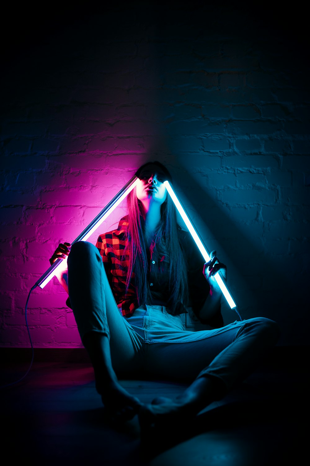 a woman sitting on the floor with a neon light