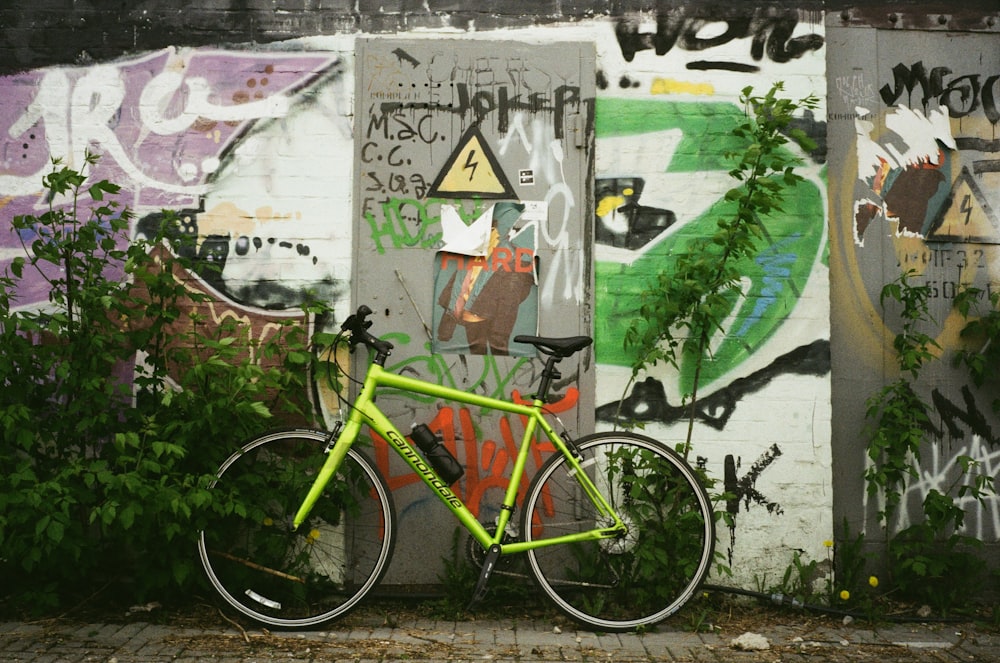 a yellow bike parked next to a wall covered in graffiti