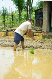 Photo of a worker preparing soil in a rural field with masonry tools nearby.