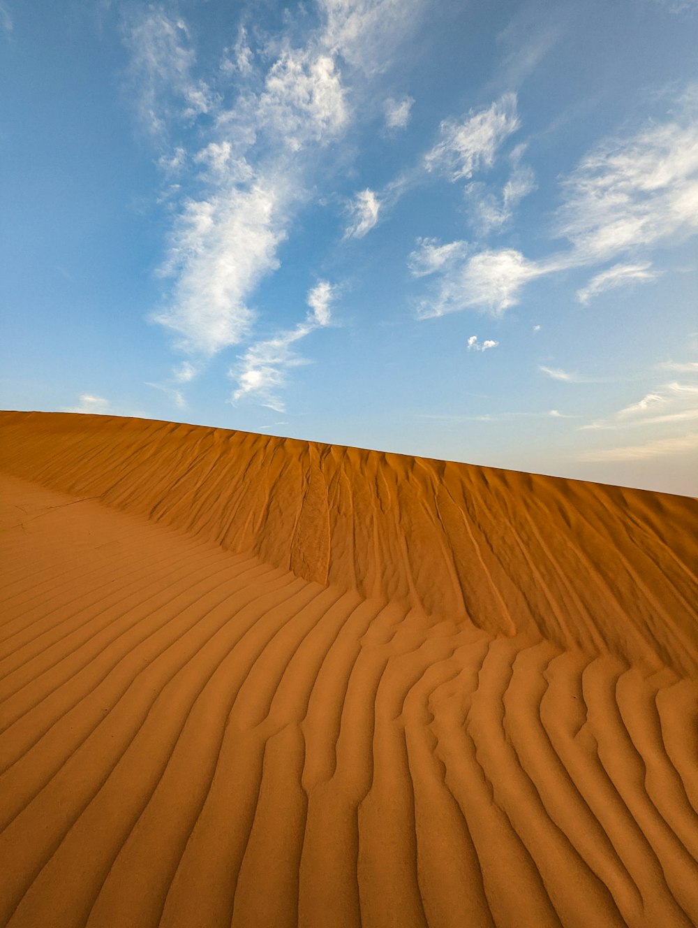 uma grande duna de areia com um céu azul no fundo