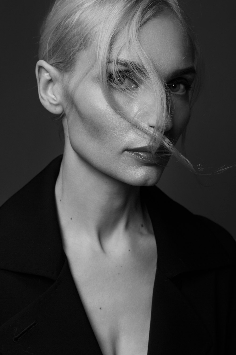 a black and white photo of a woman with her hair blowing in the wind