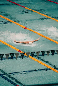 a man swimming in a pool with a white ball