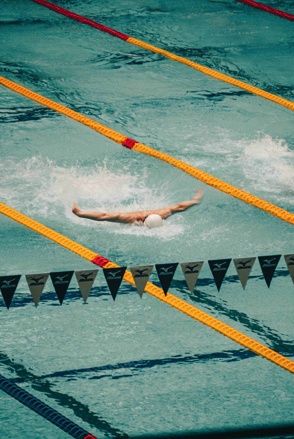 a man swimming in a pool with a white ball