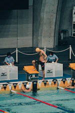 An official in uniform signaling the start of a swim race.