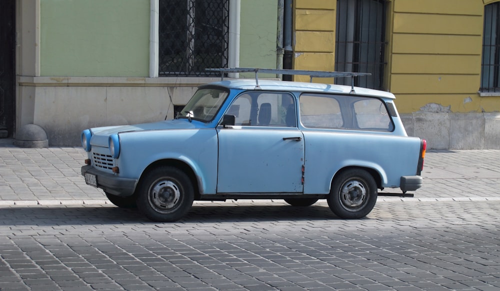 a small blue car parked on the side of the road