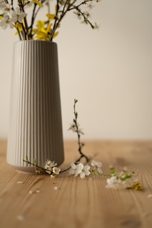 a white vase with yellow and white flowers in it