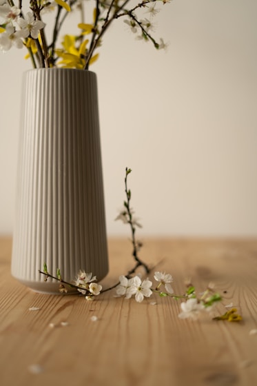 a white vase with yellow and white flowers in it