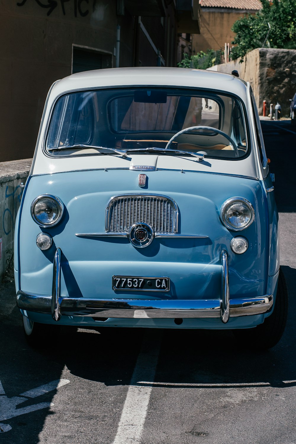 an old blue car parked in a parking lot