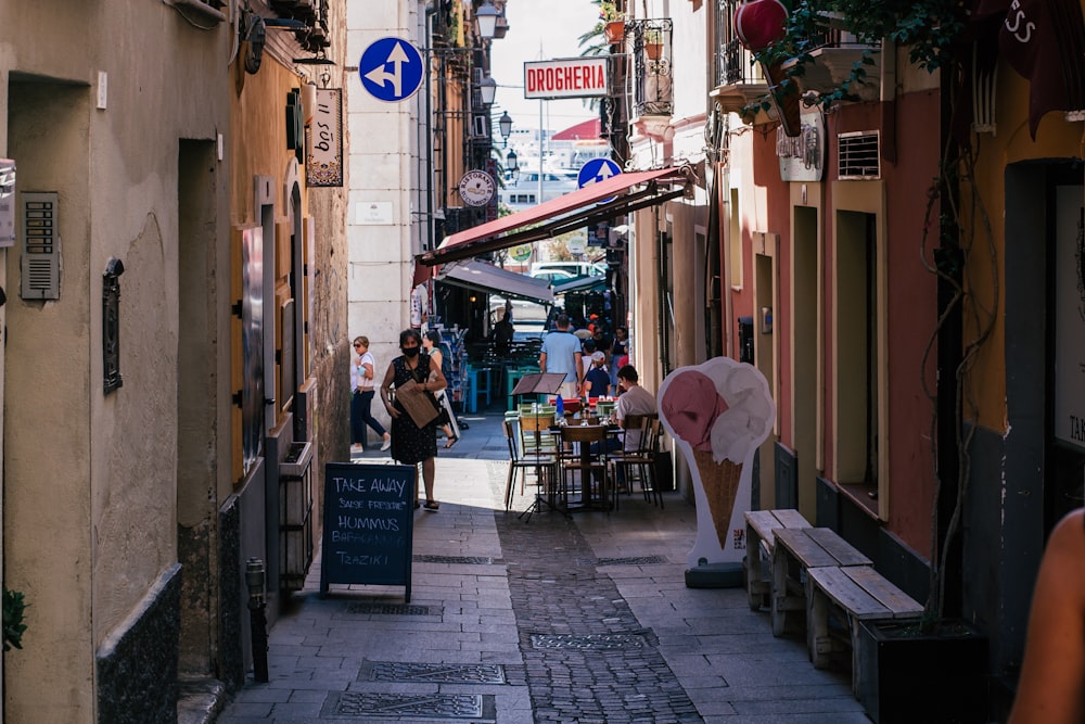 a narrow alleyway with people sitting at tables