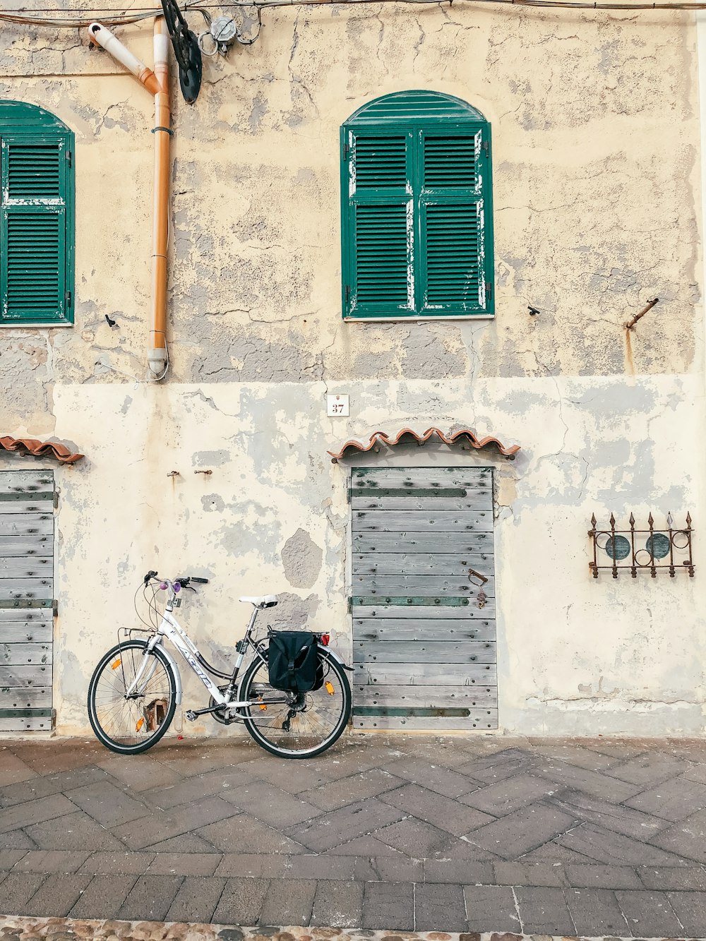 a bicycle parked in front of a building with green shutters