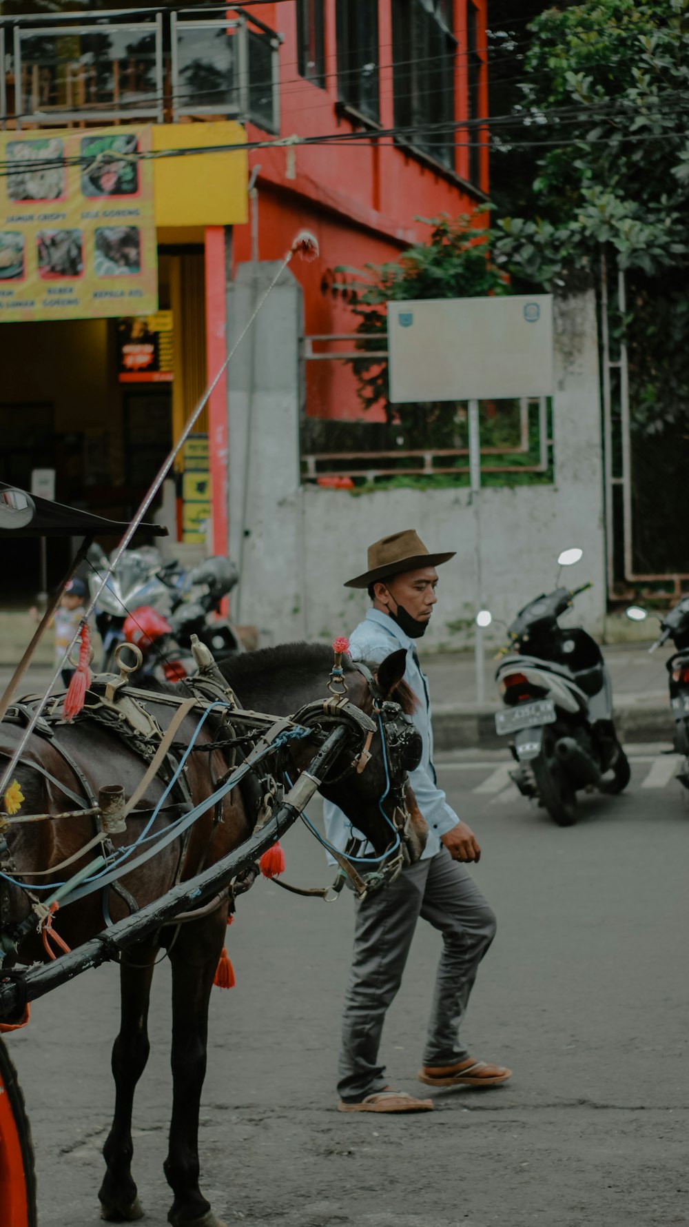 a man walking behind a horse drawn carriage