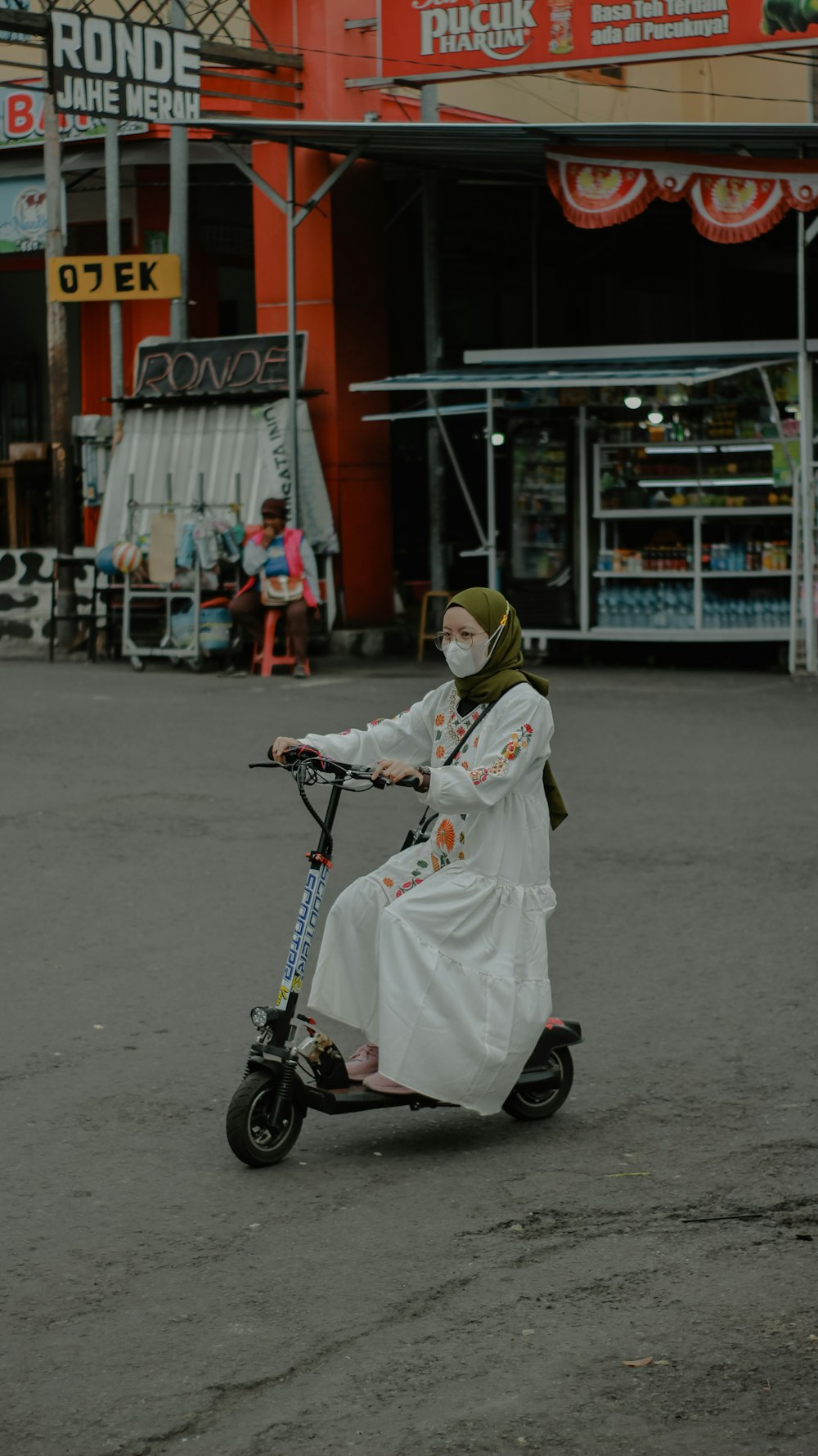 a woman in a white dress riding a scooter