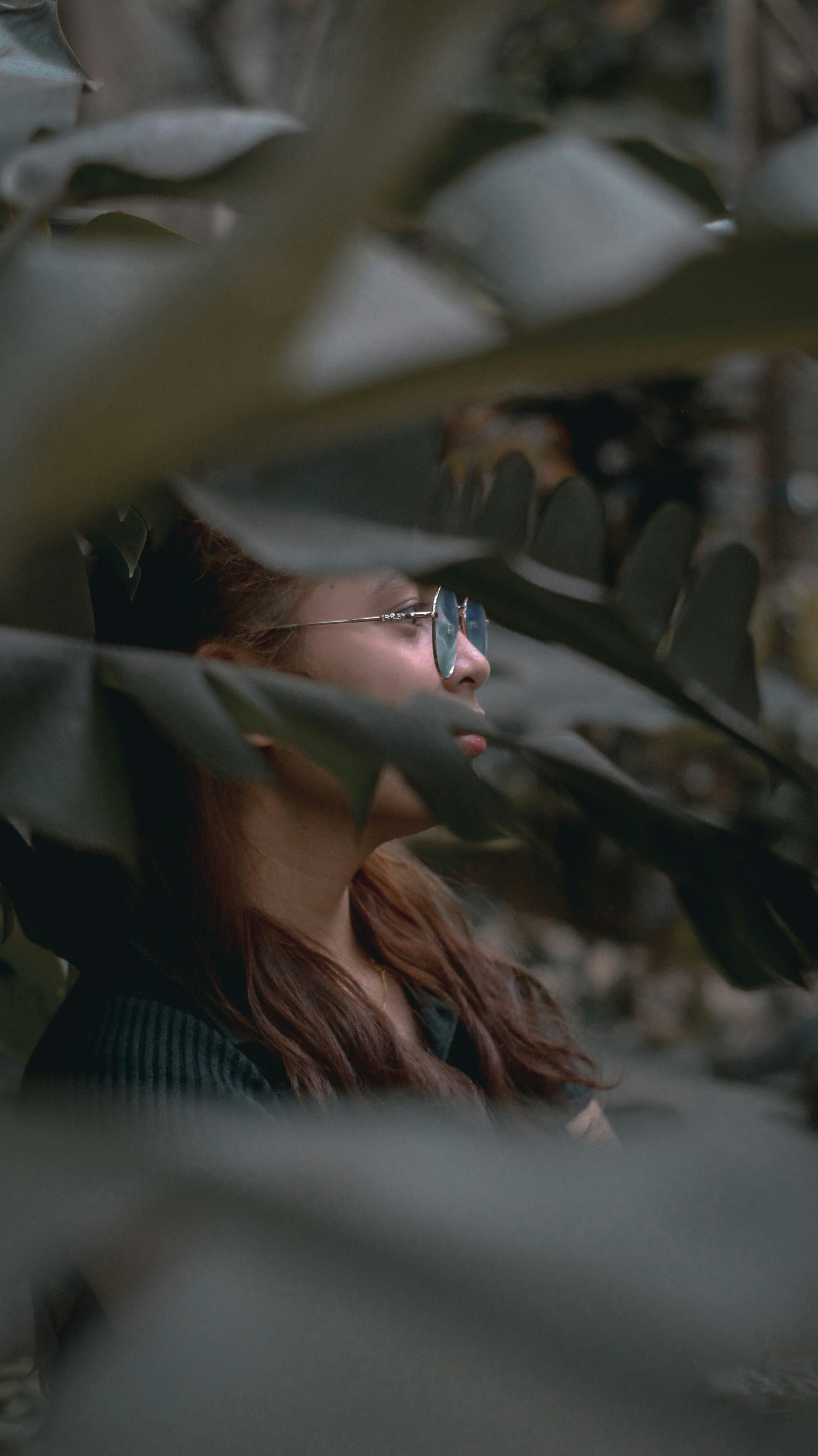 a woman wearing sunglasses standing in front of a plant