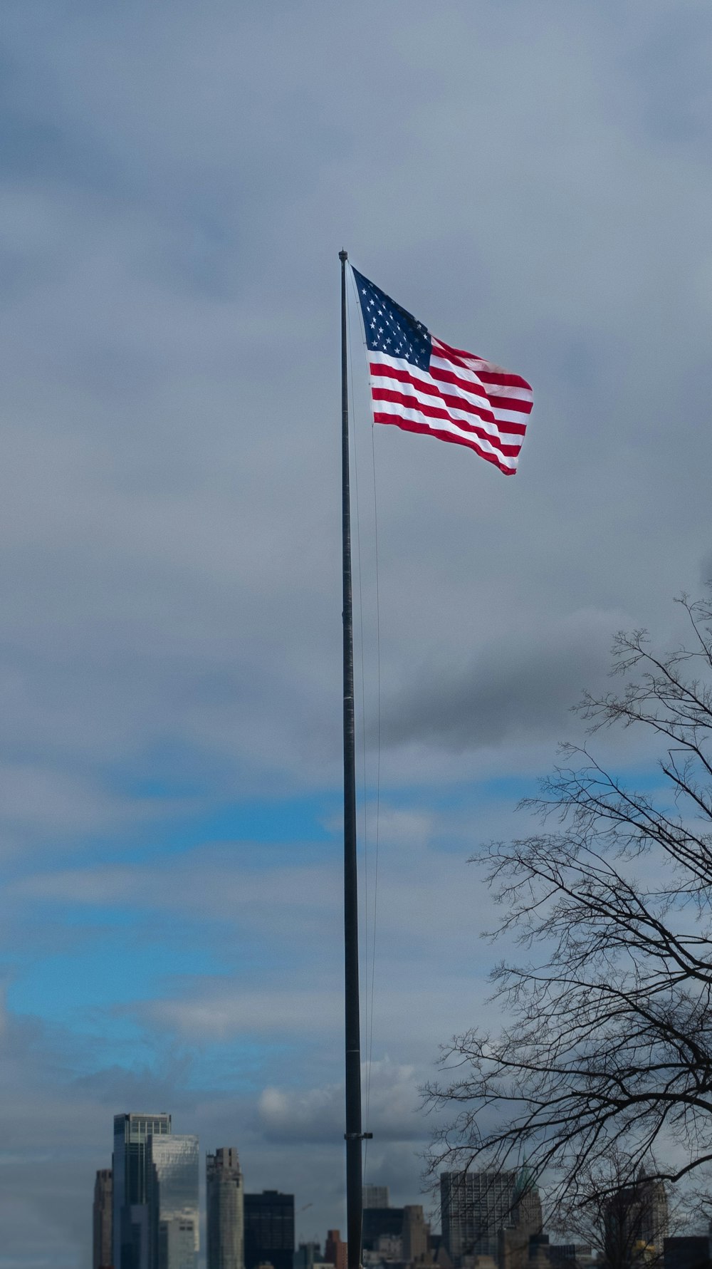 an american flag flying in the wind in front of a city skyline