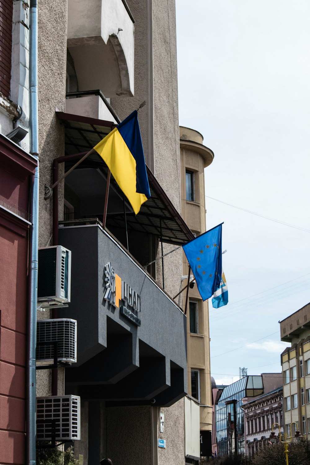 a blue and yellow flag hanging from the side of a building