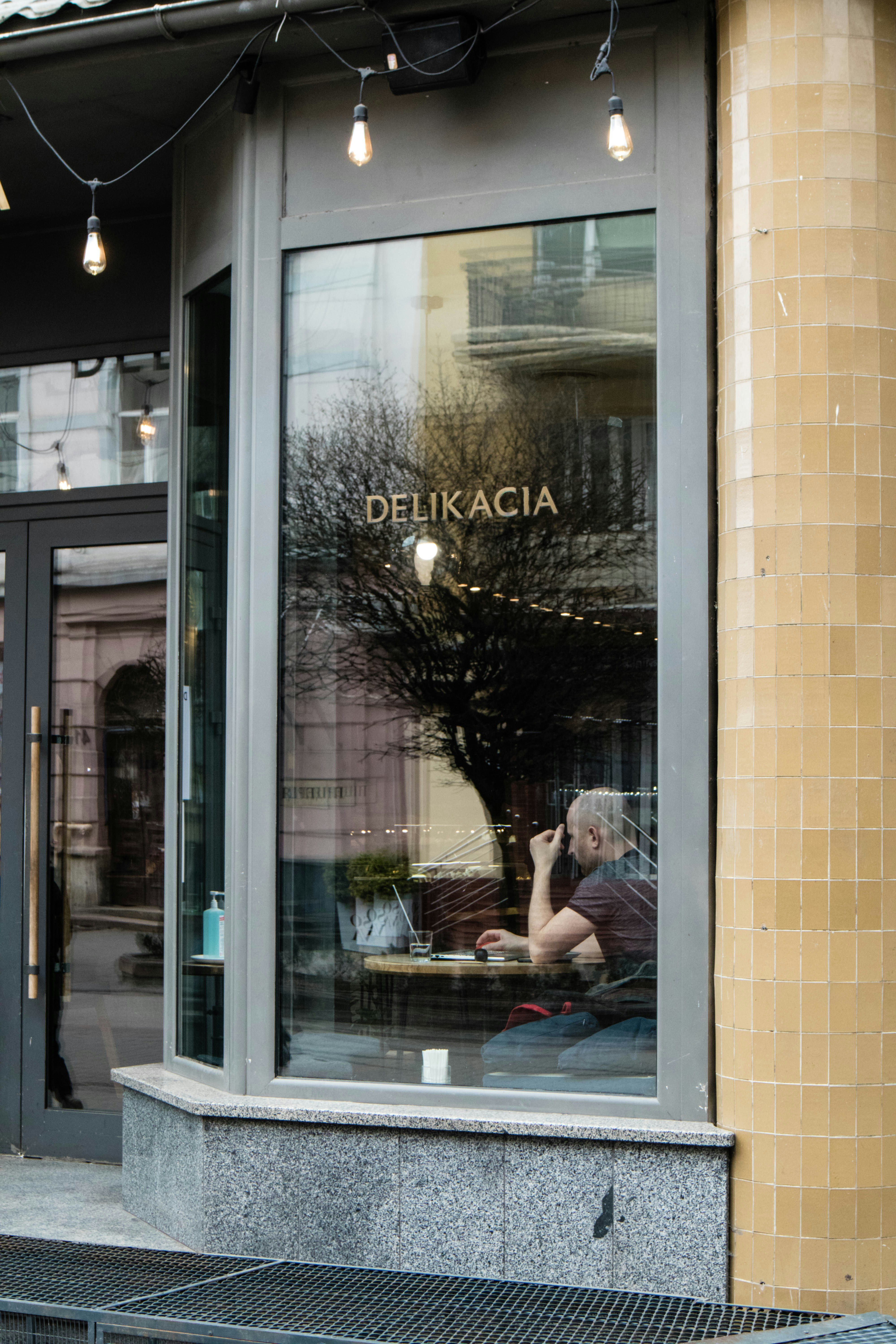 a man sitting outside of a restaurant talking on a cell phone