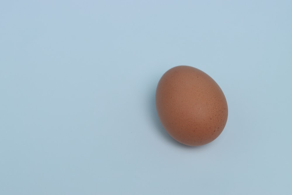 a brown egg sitting on top of a blue surface