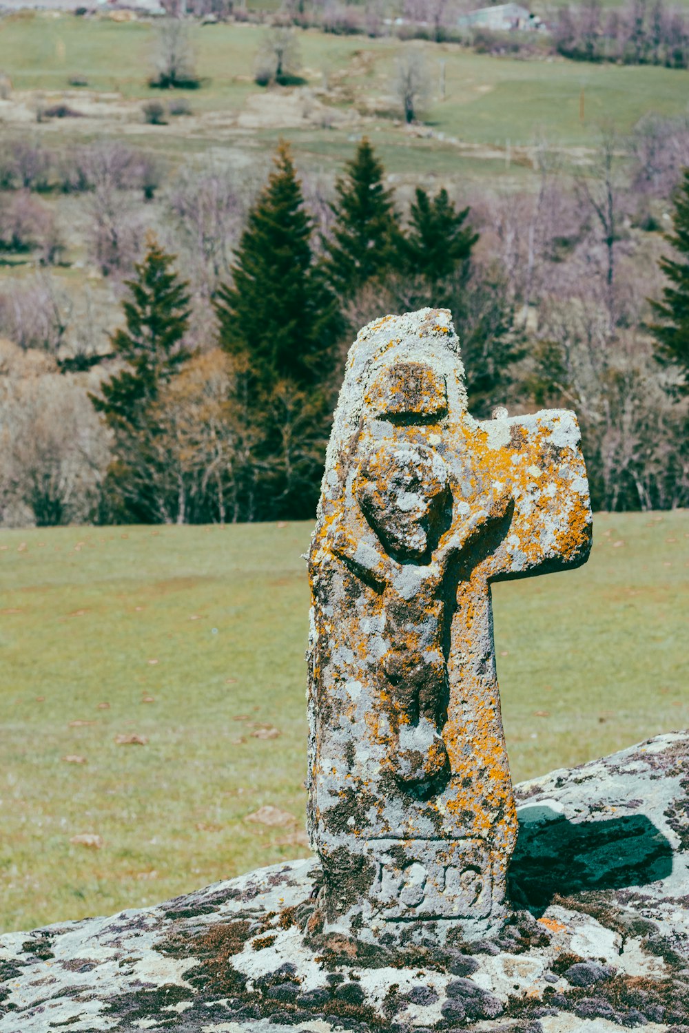 a stone cross in the middle of a field