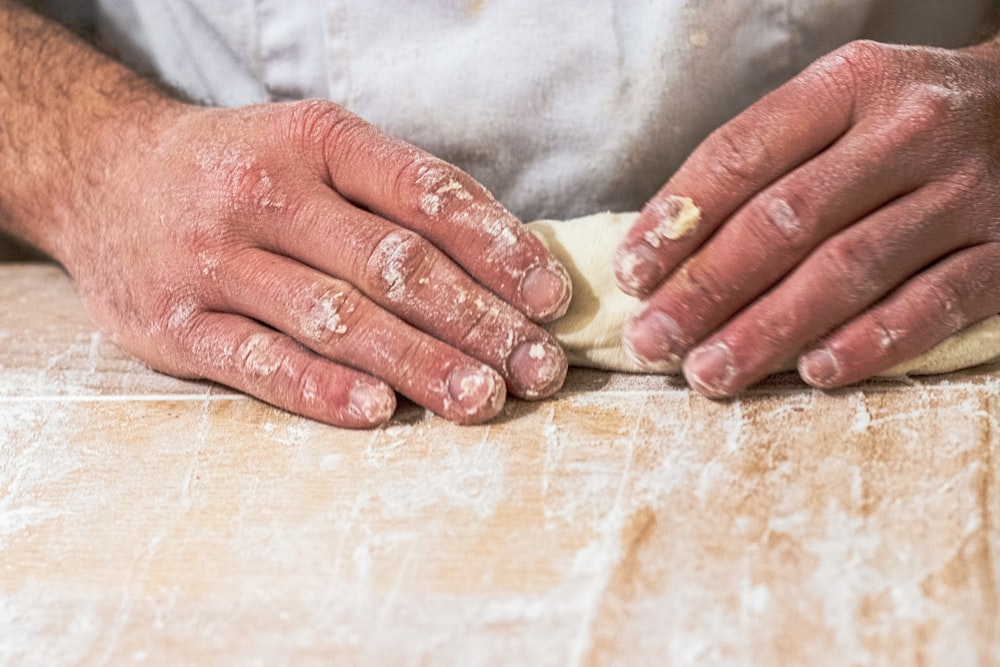 a close up of a person kneading dough on a table