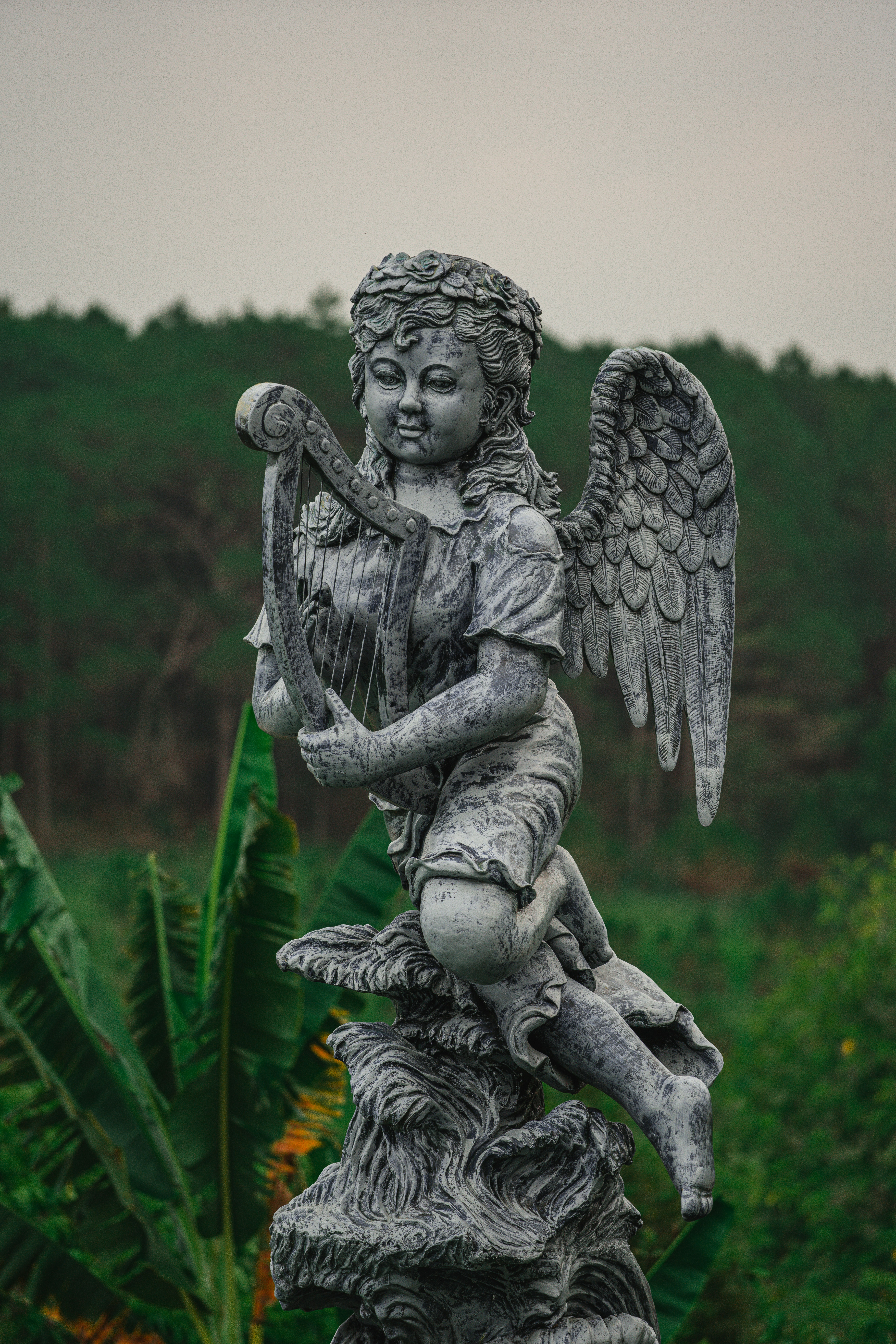 A statue of an angel sitting on top of a tree stump photo – Free ...