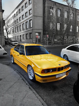 Bright yellow sedan parked by a bustling Erode street in daylight.