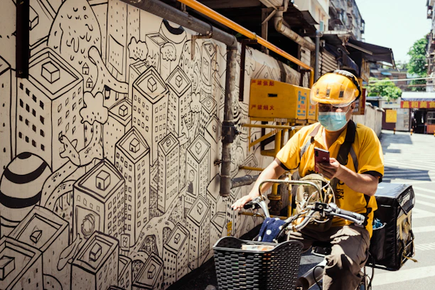 A motoboy checking his smartphone while taking a quick break on the city street.